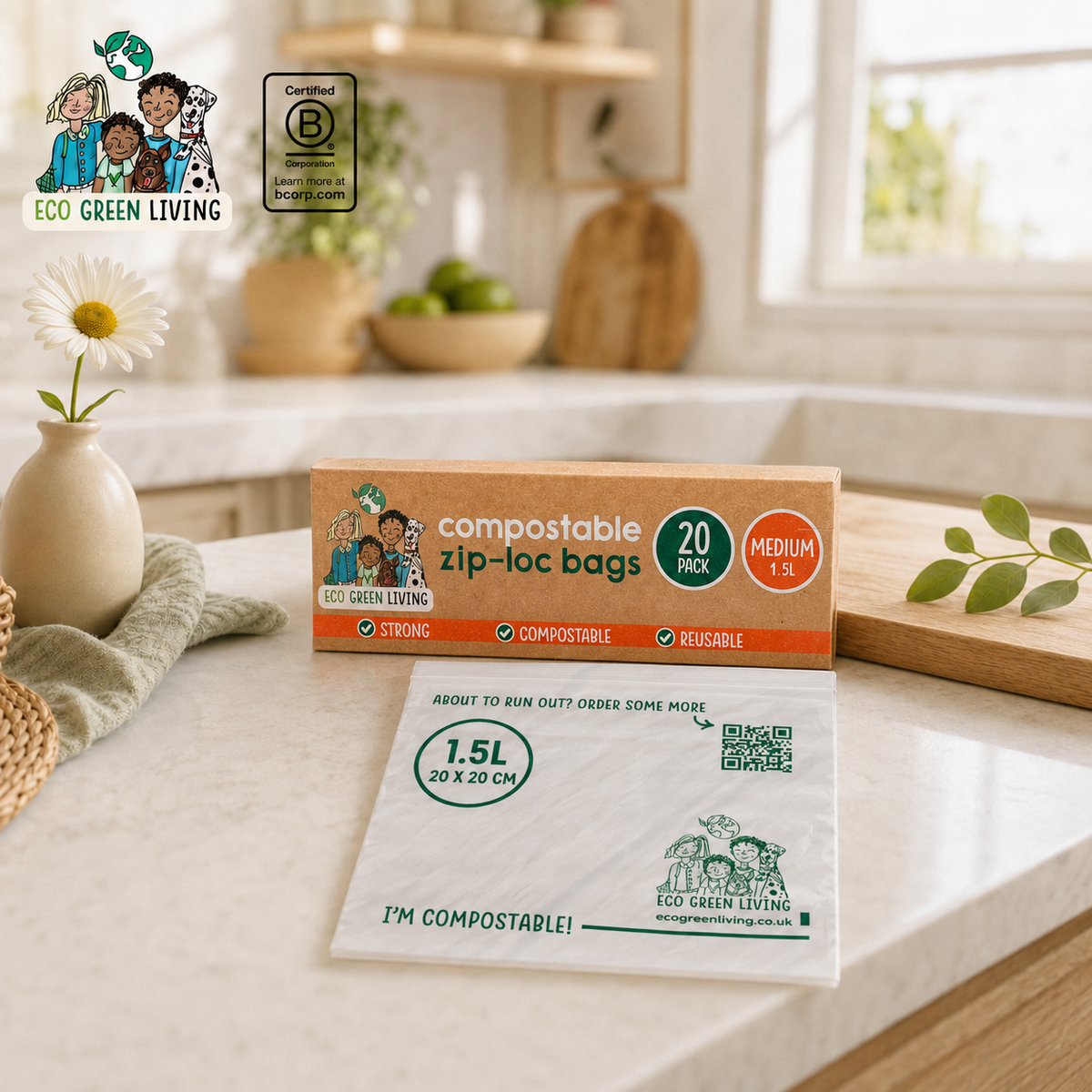 Eco Green Living compostable zip-loc bags shown on a kitchen counter with the product box and a sample bag in front. The scene includes a vase with a daisy, a wooden bowl of limes, and a softly blurred kitchen background.