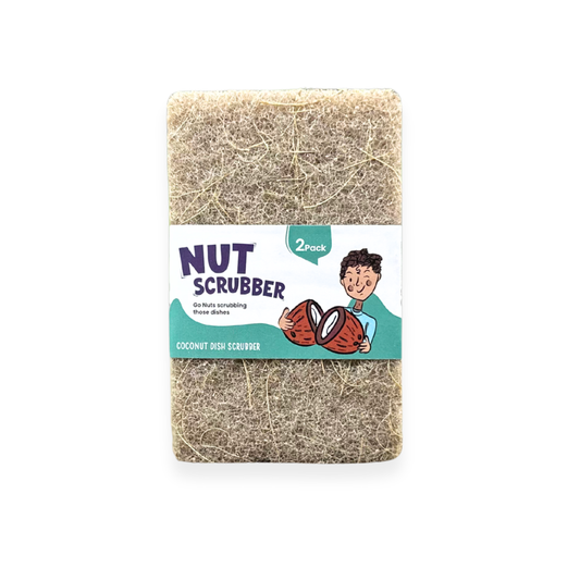 A 2-pack of coconut dish scrubbers wrapped in a white paper label with a cartoon illustration of a boy holding coconuts. The label reads 'NUT SCRUBBER' and 'COCONUT DISH SCRUBBER'.